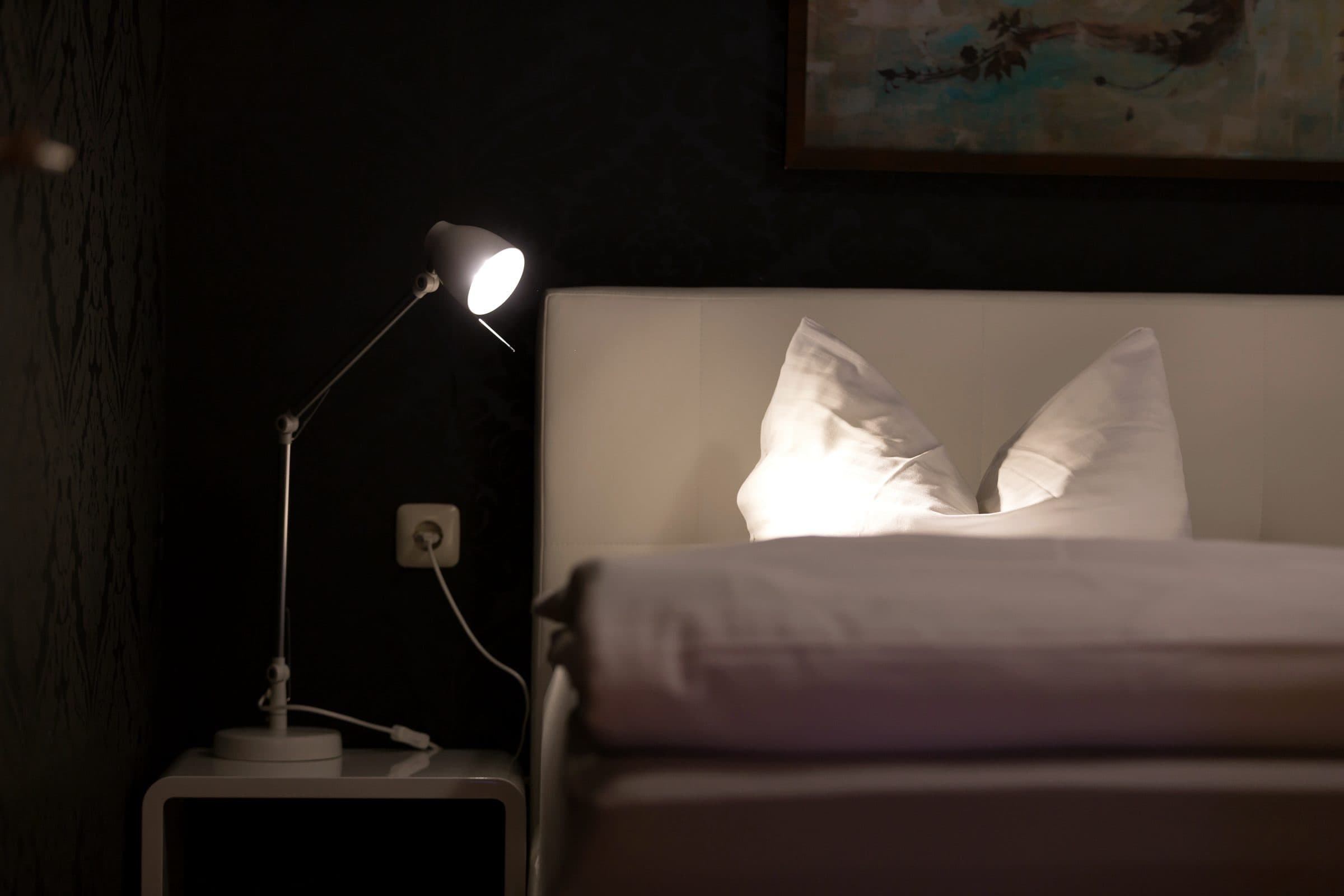 Boxspringbett mit Leselampe vor der Damasttapete